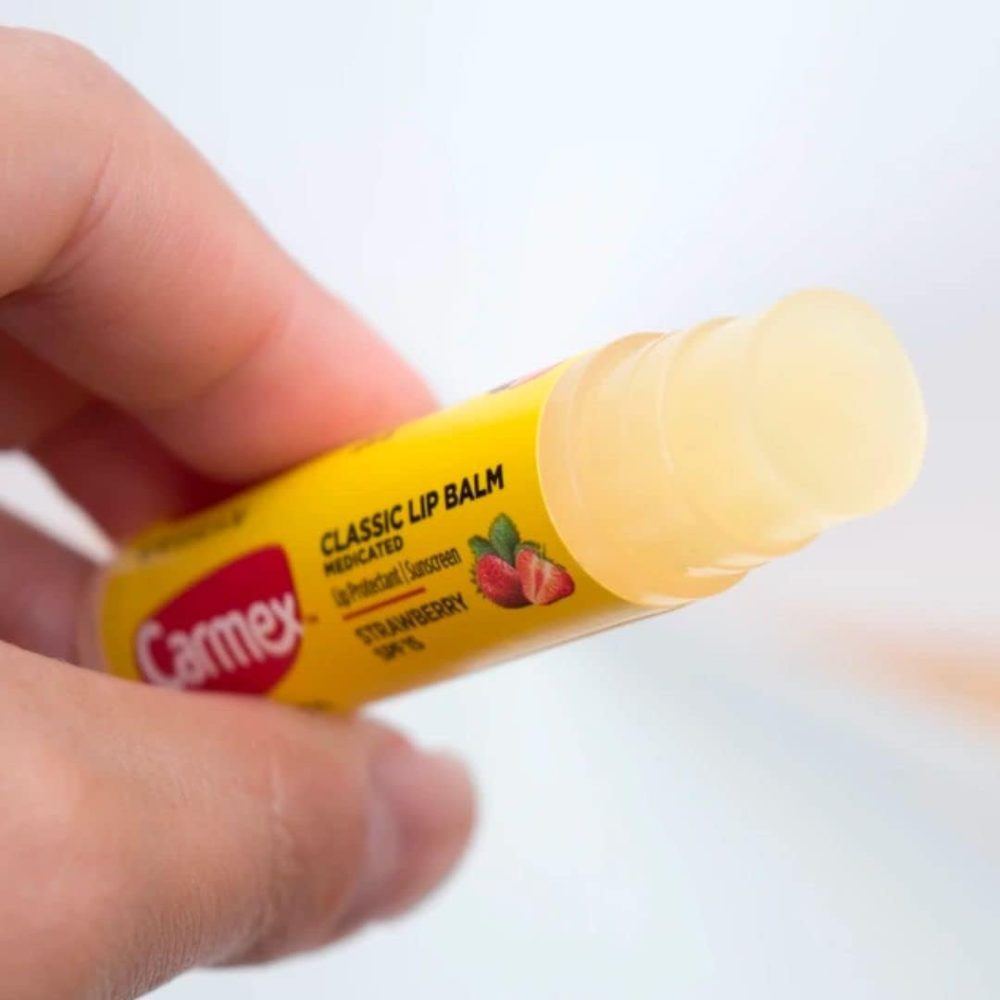 Carmex Daily Care Moisturizing Lip Balm Stick in Strawberry flavor with SPF 15, 4.25g, shown with a red and white cap.